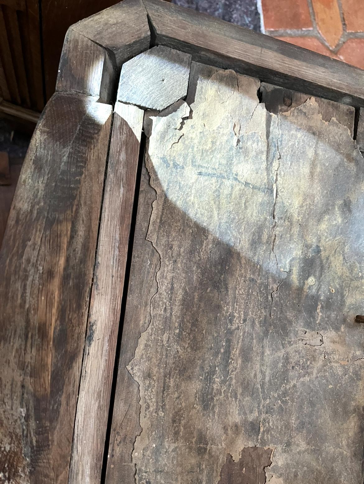 A corner of the roof at the carved octagonal joint, where the old layer is lifting and curling