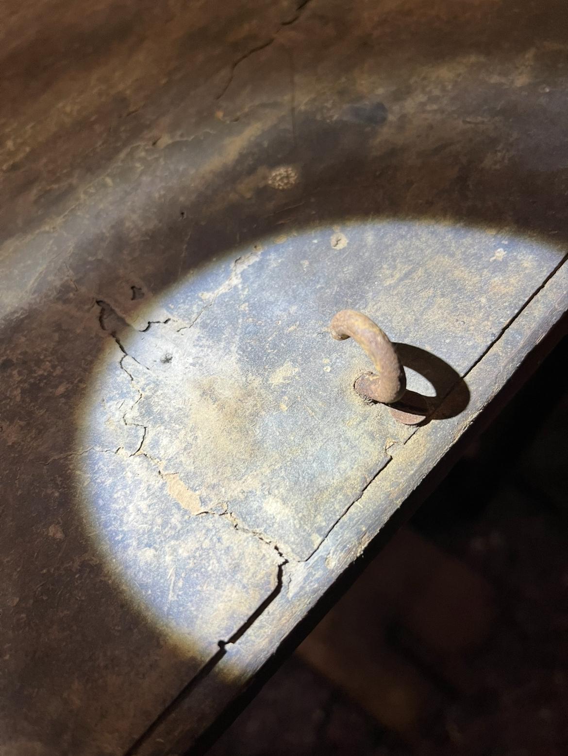 A close-up of the forged hook, surrounded by paper that has cracked into large fragments