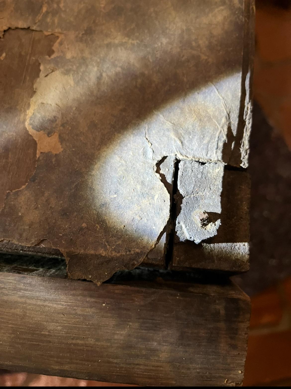 A tear near the edge of the roof, exposing bare wood beneath