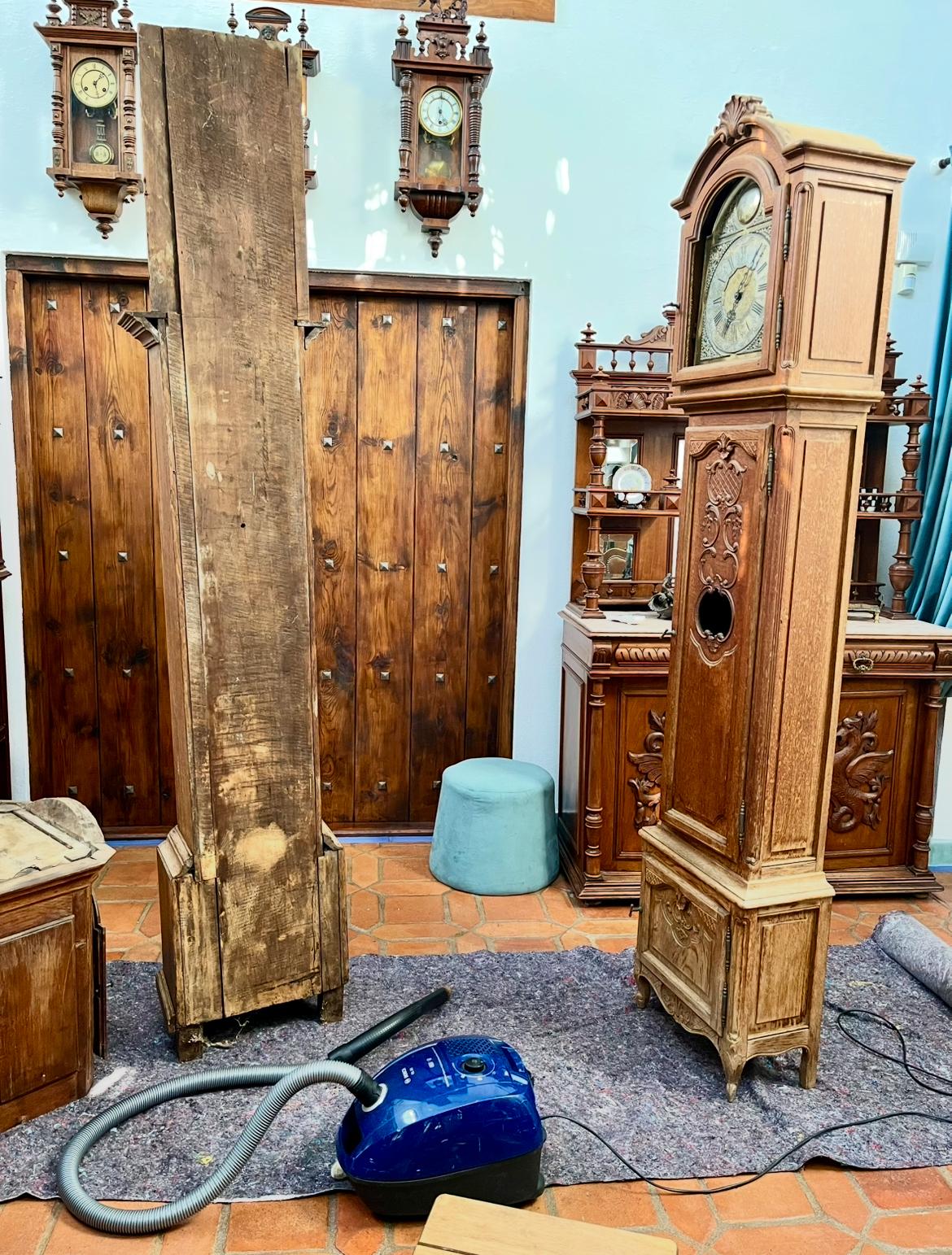 The hood and back oak panel removed, with a vacuum cleaner clearing dust out of the clock's open base