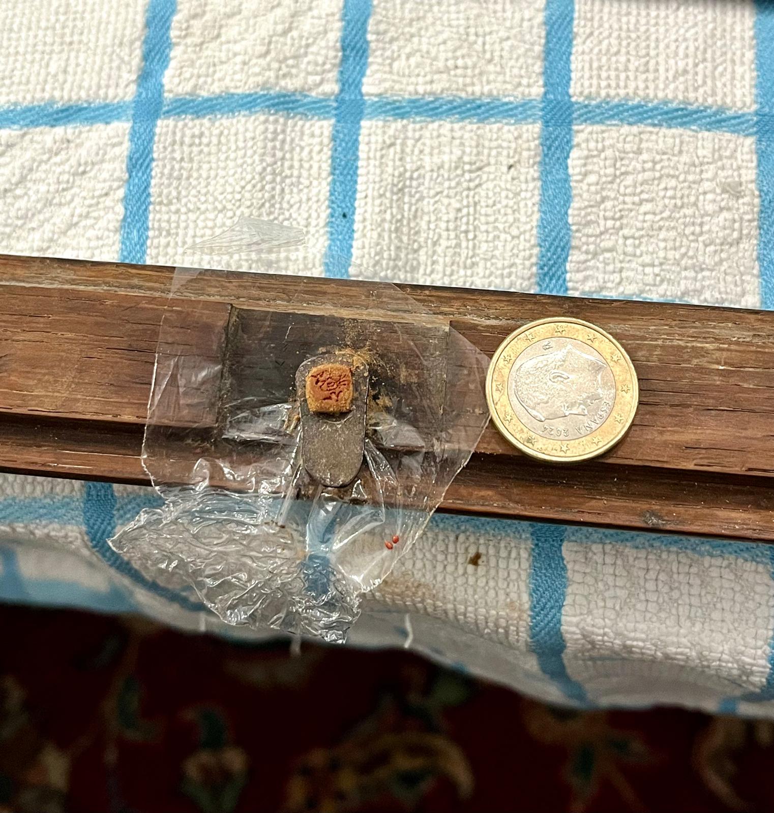 The finished latch with its bird mark, next to a coin for scale