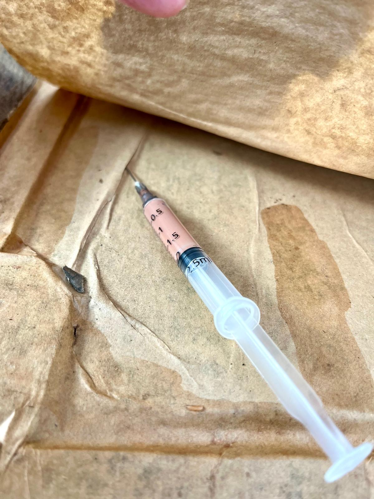 The syringe loaded with the glue mixture, needle inserted right into the gap