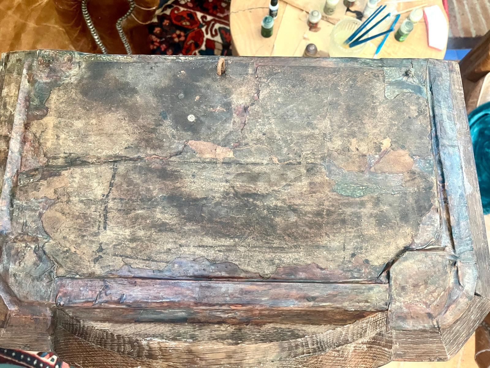 The soot-blackened paper shell of the hood's roof, overall view against the leather armchair and the oriental rug