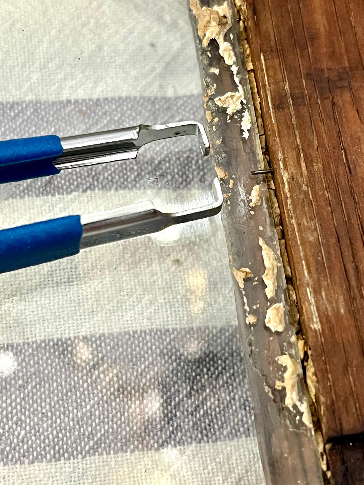 Tweezers extracting the pin, held strictly parallel to the plane of the glass
