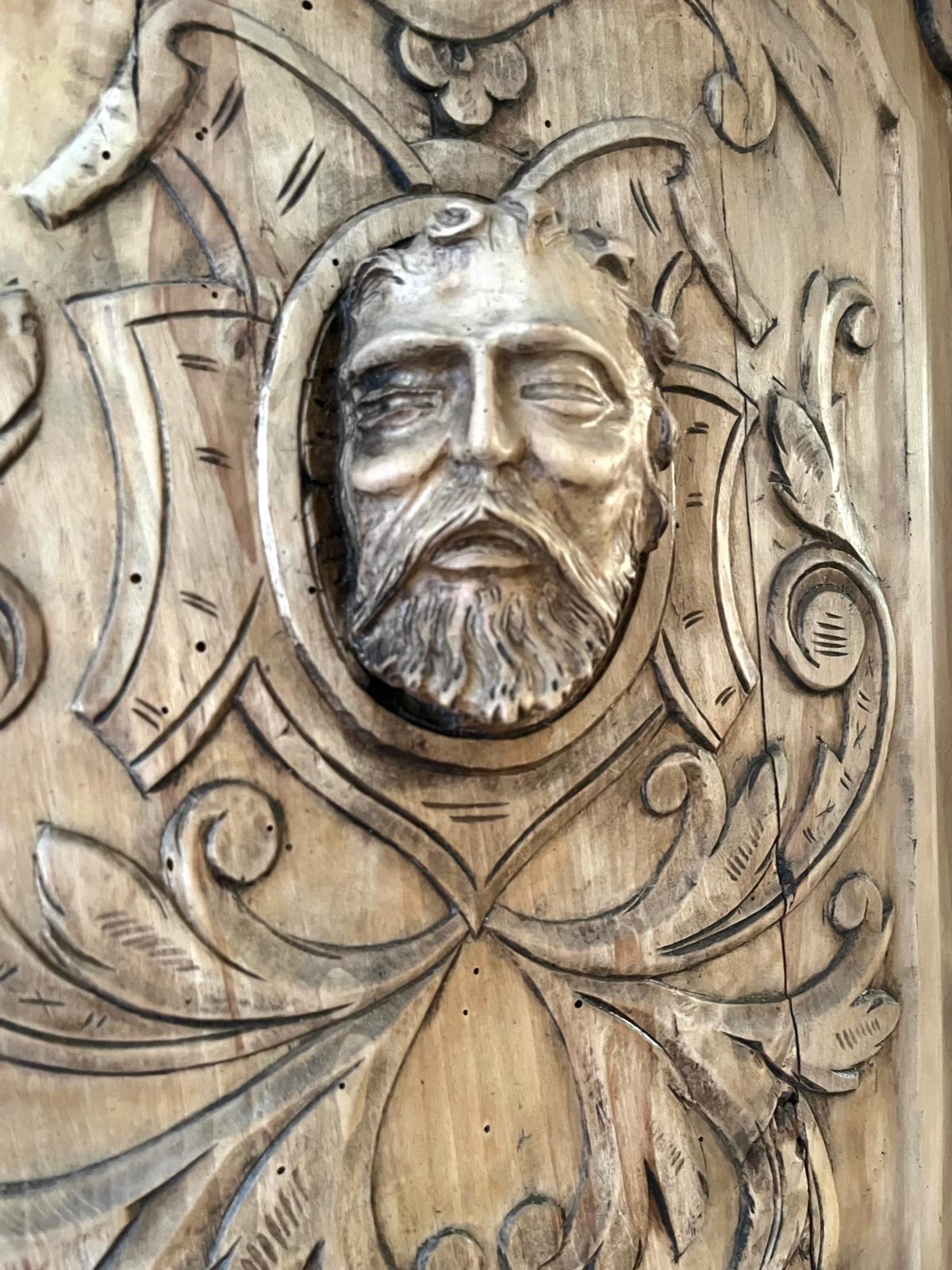 Extreme close-up of the central mascaron with a fine shrinkage crack near the edge of the panel
