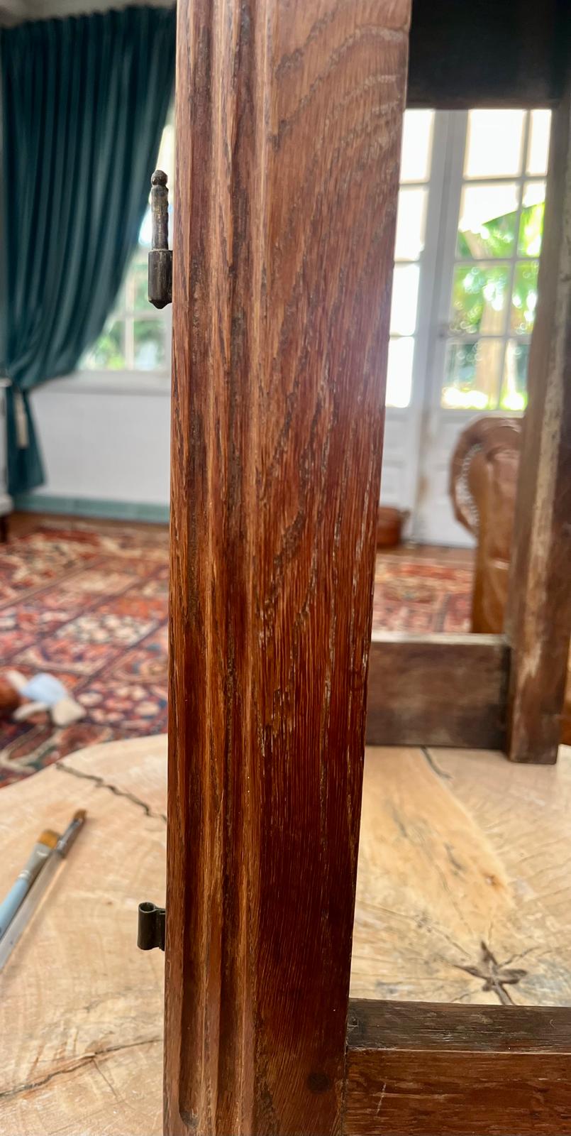Close-up of a forged brass hinge with a turned finial, mounted on a black walnut post